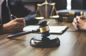 A gavel on a desk with a person in a suit in the background